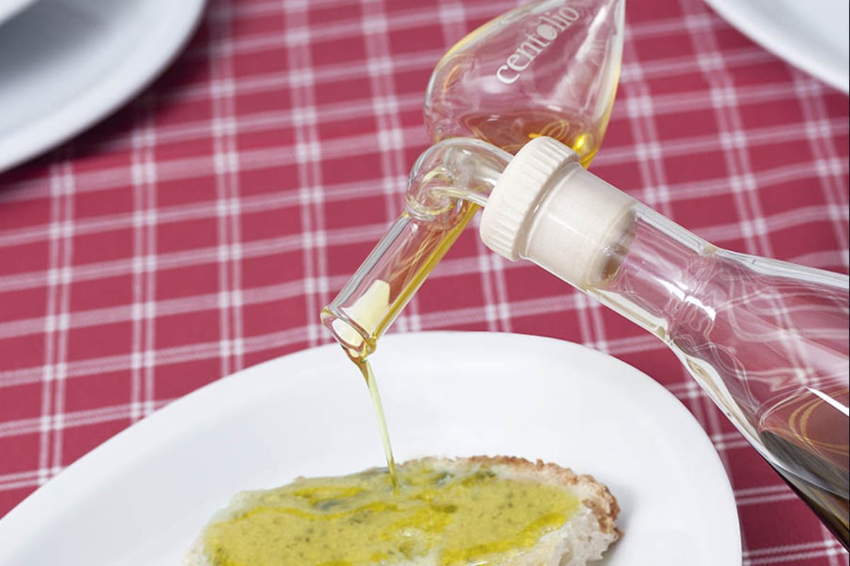 Centolio che versa olio extravergine su una fetta di pane